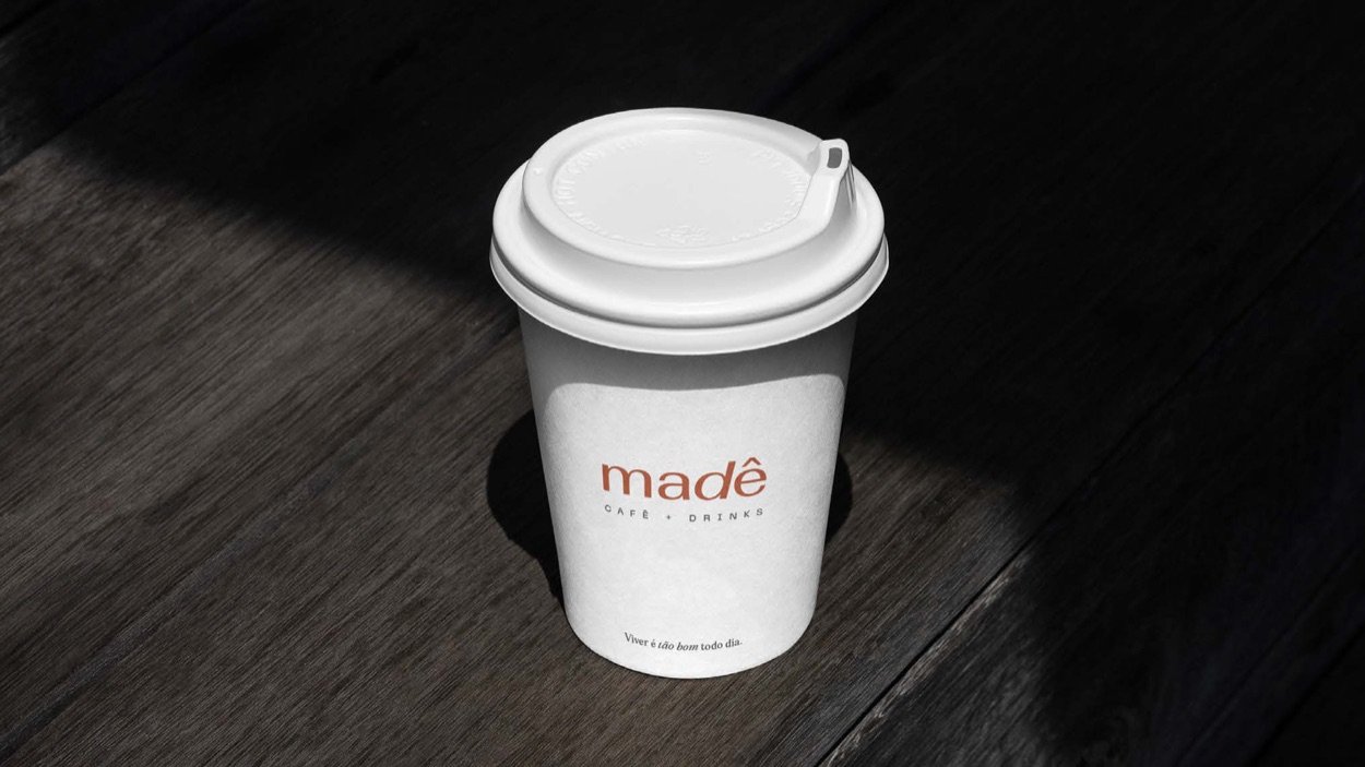Copo de café da Madê sobre mesa de madeira